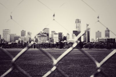 City seen through chainlink fence against sky