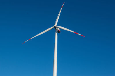 Low angle view of wind turbine against blue sky