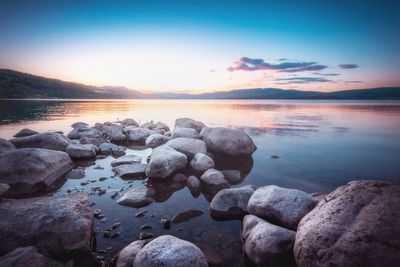 Rocks at sea shore against sky during sunset