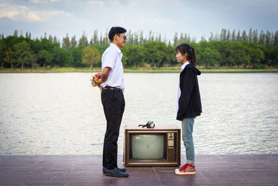 Side view of a young couple standing by lake