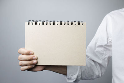 Midsection of person holding paper against white background