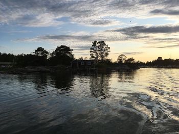 Silhouette trees by lake against sky during sunset