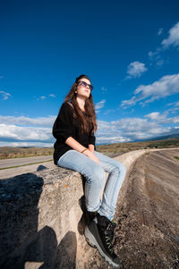 Portrait of smiling young woman sitting against blue sky