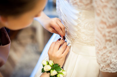 Close-up of woman assisting bride for getting dressed