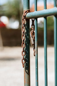 Close-up of rusty chain hanging on metallic railing