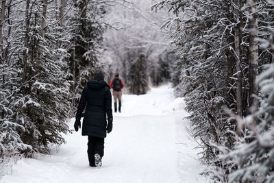 Rear view of people walking on snow covered footpath