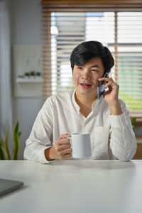 Young woman using mobile phone at desk in office