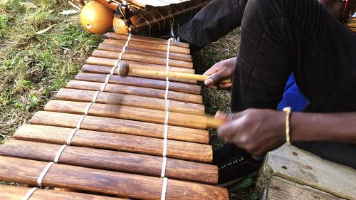 Low section of man playing wooden musical instrument