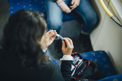 Woman checking injection pen while sitting in train
