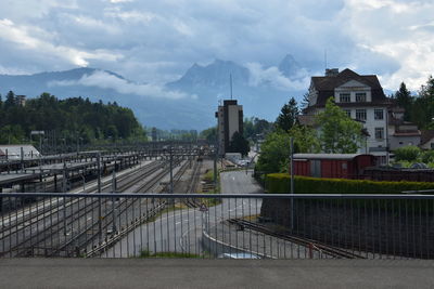 Railroad tracks at arth-rigi bahn by buildings against sky and mountain is behind.