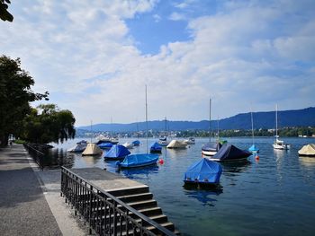 Boats moored at harbor against sky