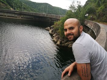 Portrait of smiling man sitting on riverbank