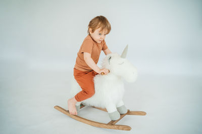 Little boy on a unicorn rocking chair on a white background. high quality photo