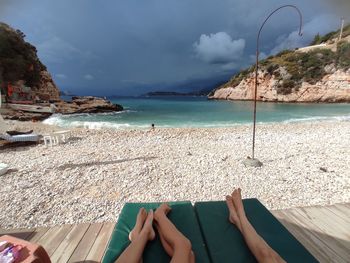 Low section of person on beach against sky