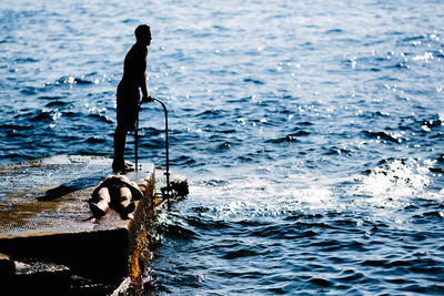 Silhouette of man with fishing net in sea