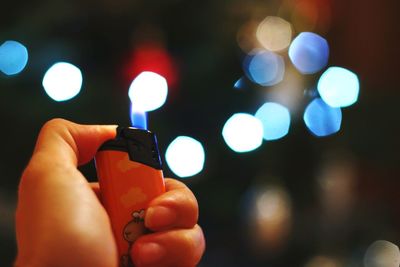 Close-up of hand holding illuminated lighting equipment