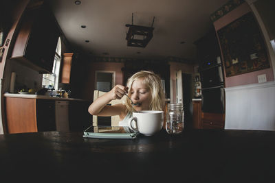 Girl having food while looking at tablet computer on table