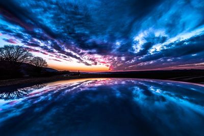 Digital composite image of dramatic sky over lake during sunset