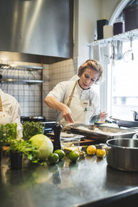 Female chef preparing food in tray at commercial kitchen