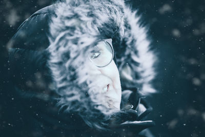 Close-up portrait of young woman in warm clothing during water