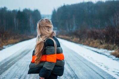 Rear view of woman on snow covered road