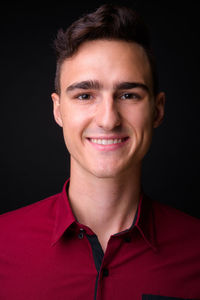 Portrait of smiling young man against black background