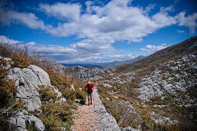 Rear view of man walking on mountain against sky