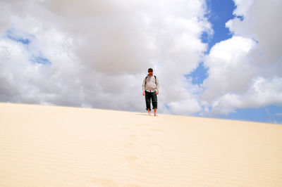 Woman standing on landscape against cloudy sky