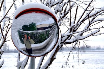 Reflection of man seen in road mirror during winter