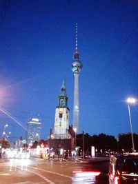 Illuminated city against clear blue sky at night