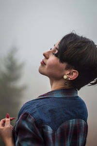 Portrait of woman holding hands against sky