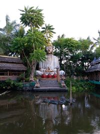 Statue by palm trees against sky