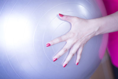 Cropped hand of woman holding fitness ball in gym