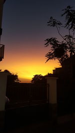 Silhouette trees and buildings against sky during sunset