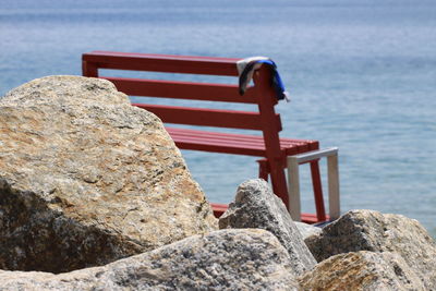 Close-up of bench on rock by sea