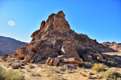 Rock formations on landscape against clear blue sky