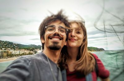 Portrait of smiling young couple standing against sea