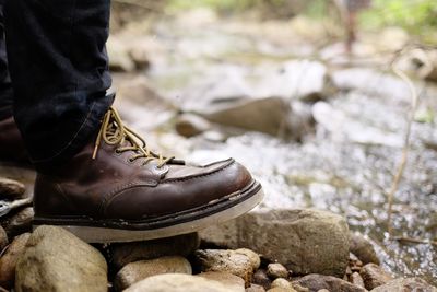 Low section of man wearing shoes on rock