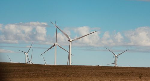 Windmills on field against sky