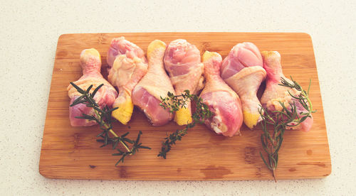 High angle view of raw meat with herbs on cutting board