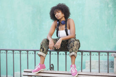 Young woman looking down while sitting on railing