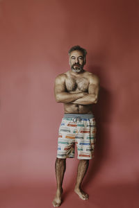 Portrait of young man standing against colored background