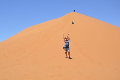 Portrait of woman standing on desert against clear sky