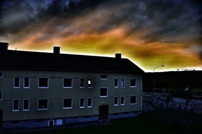 Silhouette of buildings against cloudy sky at sunset