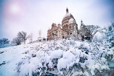 Low angle view of trees and building against sky during winter