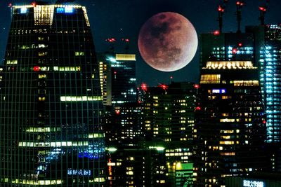 Illuminated cityscape against sky at night