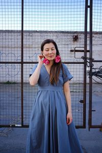 Portrait of a smiling young woman standing against fence