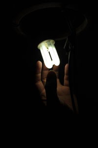 Close-up of hand holding illuminated electric lamp