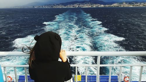 Rear view of girl standing in boat on sea