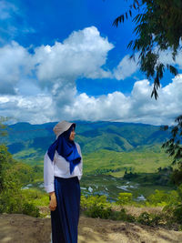Rear view of woman standing on mountain against sky